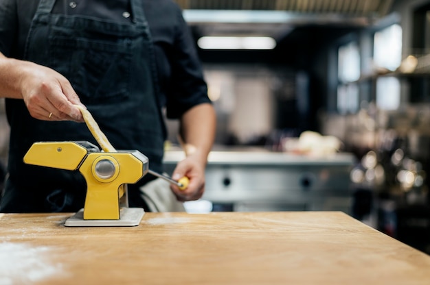 Free Photo male chef rolling fresh pasta dough