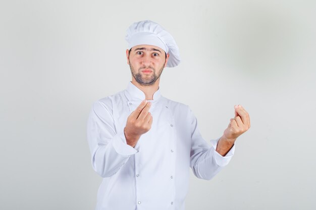 Male chef showing gesture with hands in white uniform and looking confused