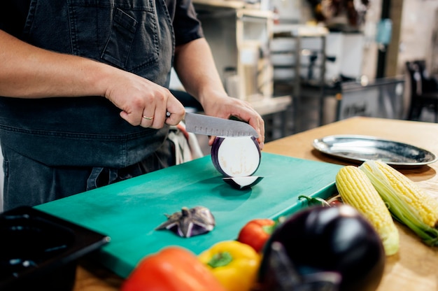 Male chef slicing aubergine in the kitchen