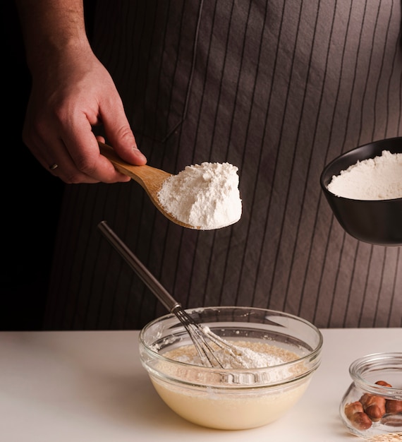 Male cook adding flour to mixture