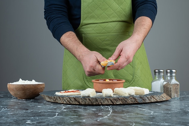 Male cook cuts orange into the pieces on marble table.