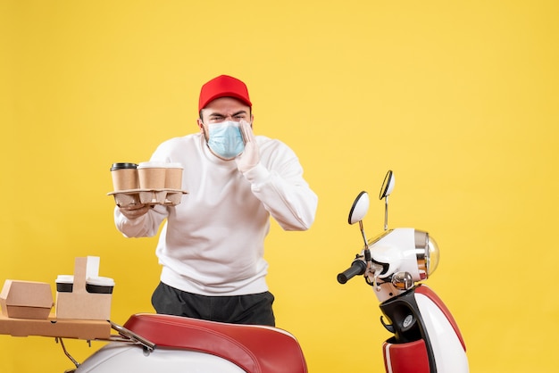 Free photo male courier in mask holding coffee on yellow