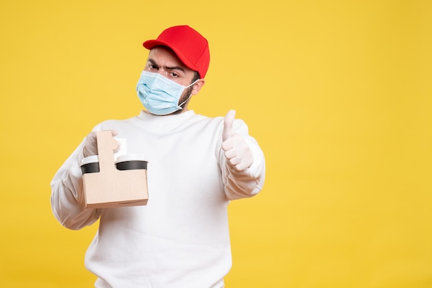 male courier in mask holding delivery coffee on yellow