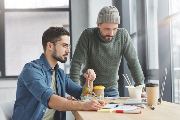 Free photo male coworkers in office with lunch