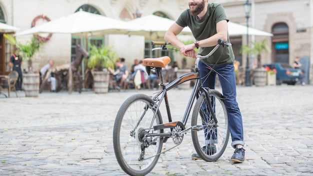 Free photo male cyclist with bicycle standing on city street