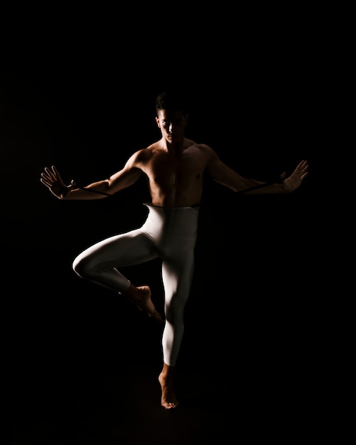 Free photo male dancer standing against black background with extended hands