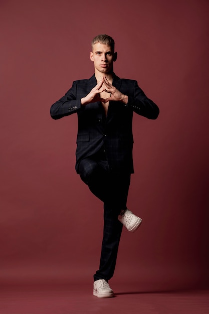 Free photo male dancer in suit and sneakers making yoga pose