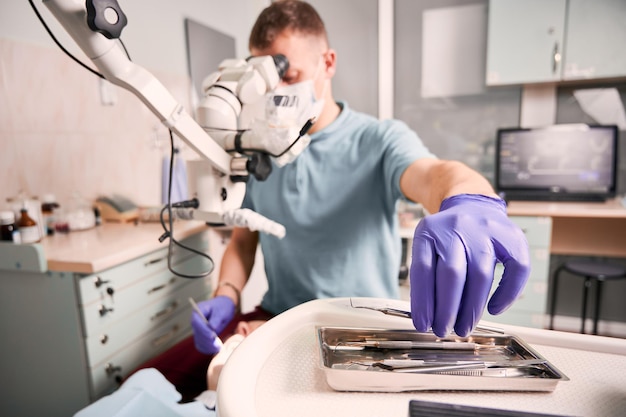 Male dentist grabbing dental explorer during dental procedure