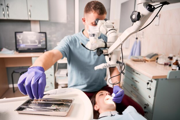 Male dentist grabbing dental explorer during dental procedure