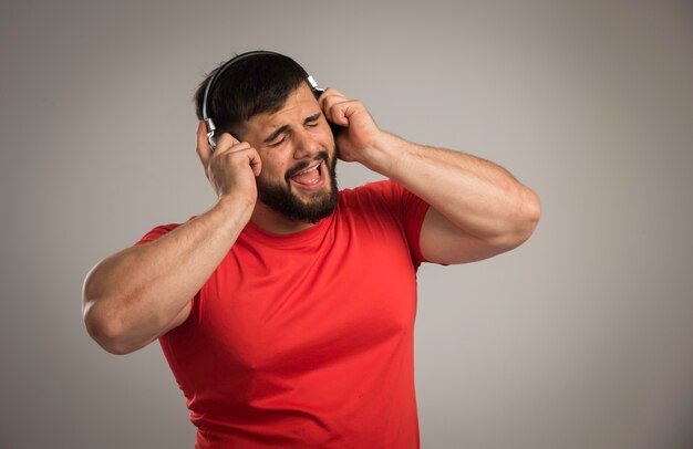 Male dj in red shirt wearing headphones and singing. 