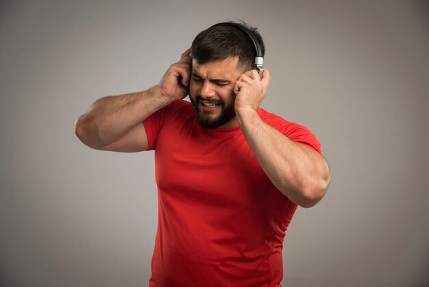 Male dj in red shirt wearing headphones and singing. 