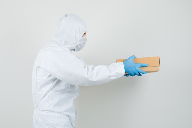 Male doctor delivering cardboard box in protective suit