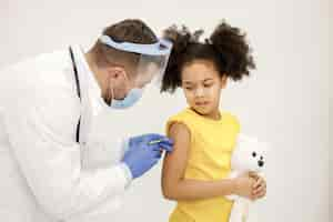 Free photo male doctor doing a vaccination to a black girl isolated on white backgriound