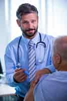 Free photo male doctor giving an injection to a patient at the hospital