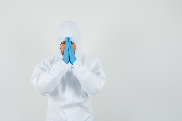 Male doctor holding hands in praying gesture in protective suit