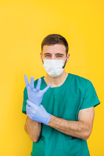 Free Photo male doctor in mask putting on sterile gloves 