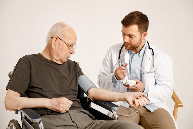 Male doctor and old man on a wheelchair isolated on a white background