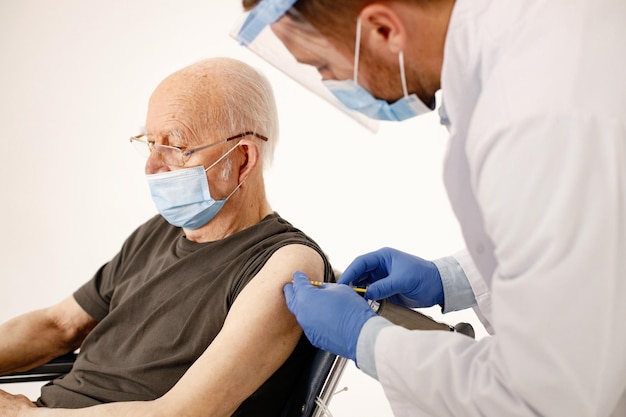 Male doctor and old man on a wheelchair isolated on a white background