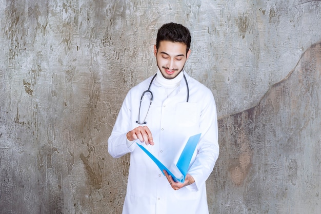 Free photo male doctor with stethoscope holding a blue folder