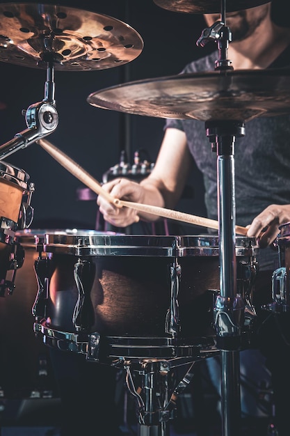 A male drummer plays the drums in a dark room