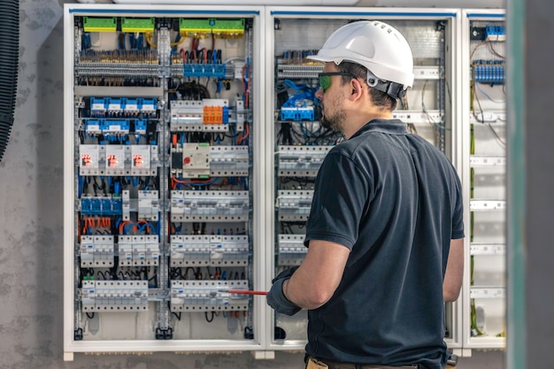 Free photo a male electrician works in a switchboard using an electrical connection cable