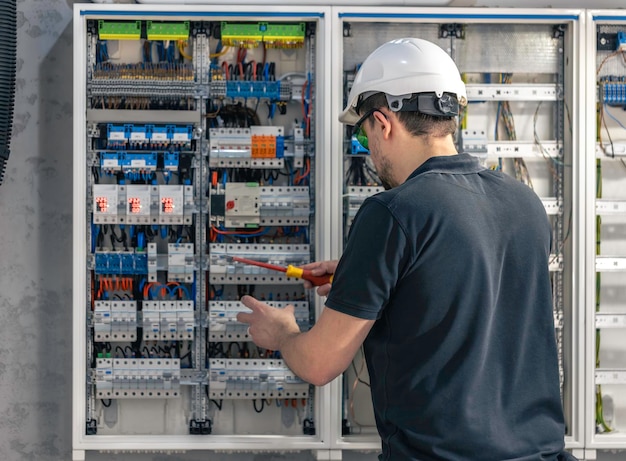 Free photo a male electrician works in a switchboard using an electrical connection cable