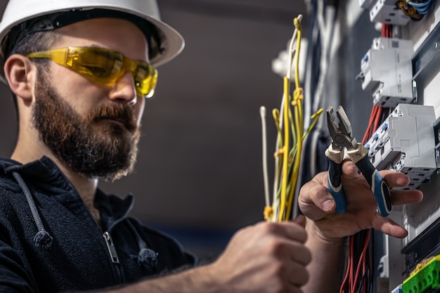 Free photo a male electrician works in a switchboard with an electrical connecting cable