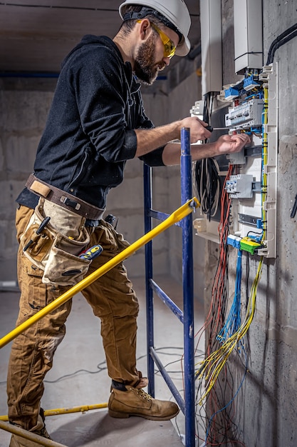 Free Photo a male electrician works in a switchboard with an electrical connecting cable.