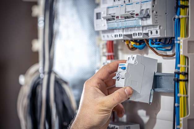 Free Photo a male electrician works in a switchboard with an electrical connecting cable