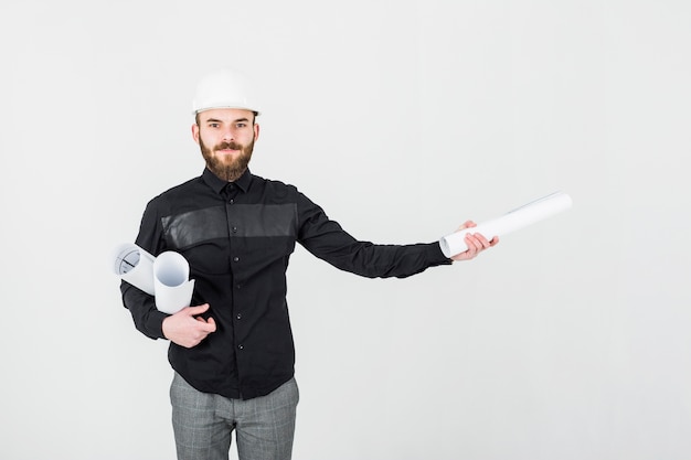 Male engineer holding layout plan against white background