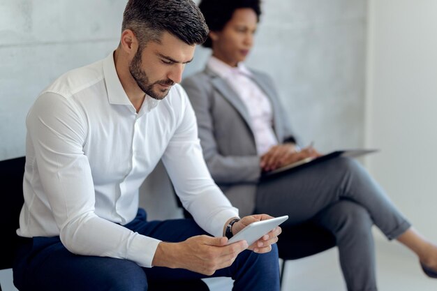 Male entrepreneur using touchpad while waiting for job interview