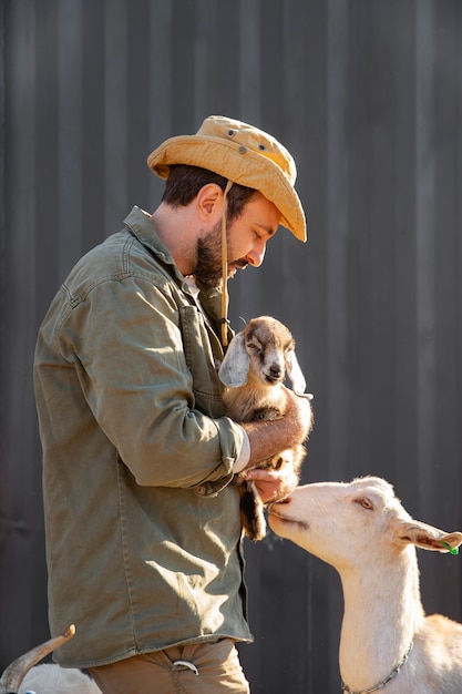 Free Photo male farmer tending to his goats at the farm