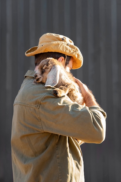 Free Photo male farmer tending to his goats at the farm