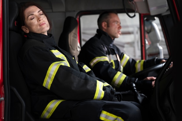 Free photo male and female firefighter at the station in fire truck