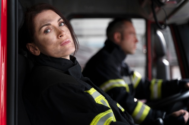 Free photo male and female firefighter at the station in fire truck