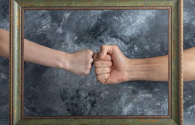 Male and female fists meets in middle of picture frame.