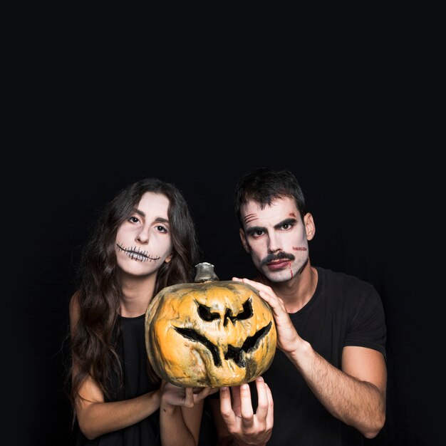 Male and female friends with creepy pumpkin