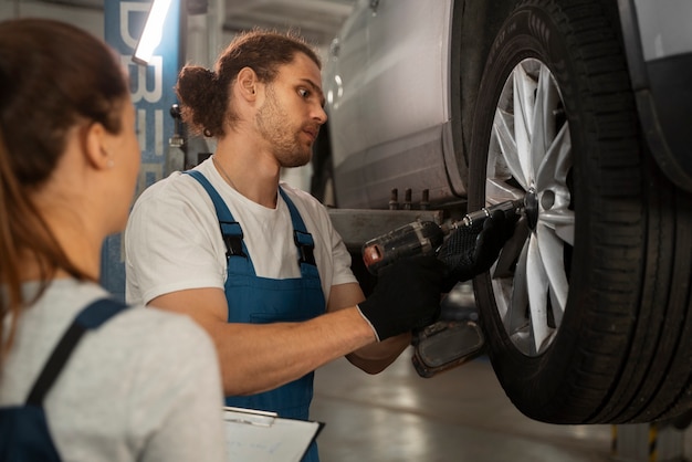 Free photo male and female mechanics working in the shop on a car