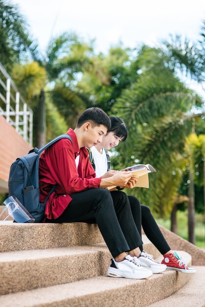 Male and female students sitting and reading books on the stairs.