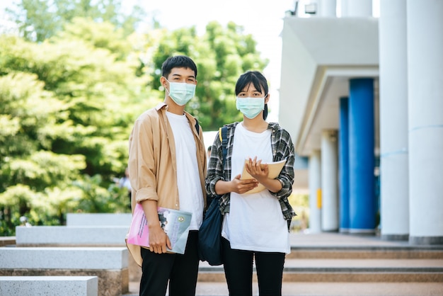 Male and female students wear a health mask and talk to each other on the stairs.