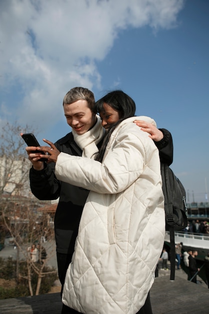 Male and female tourists checking their smartphone outdoors