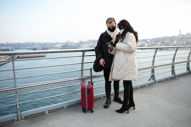 Male and female tourists checking their smartphone outdoors