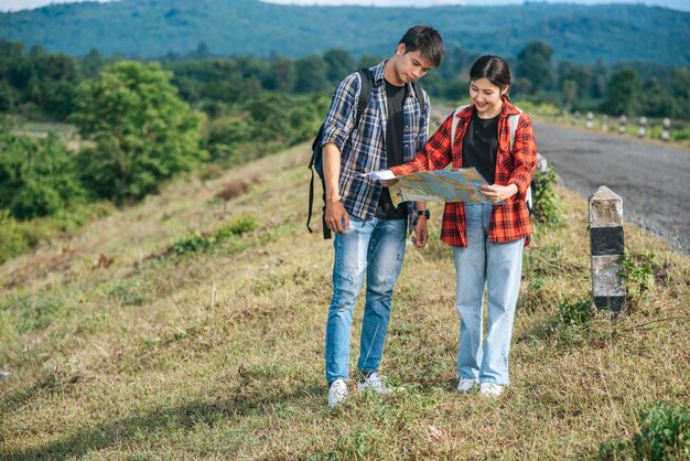 Male and female tourists standing look at the roadside map.