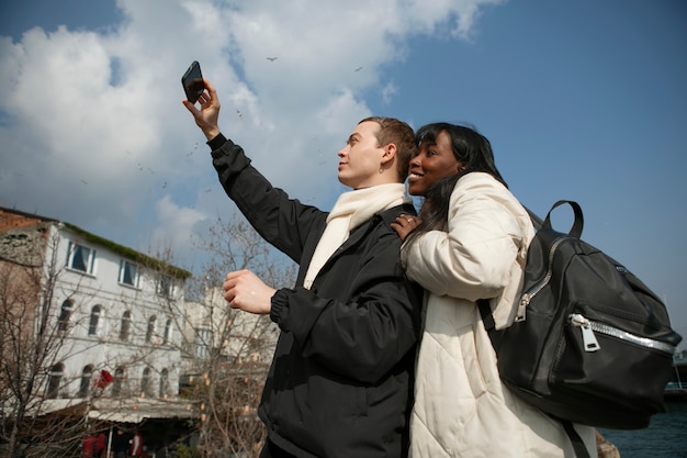 Male and female tourists taking a selfie outdoors with their smartphone