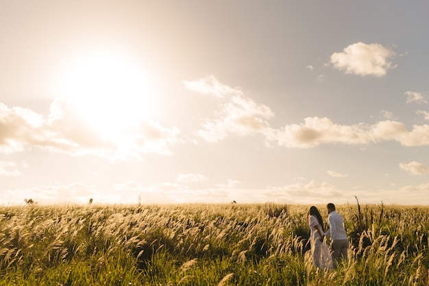 Free photo male and a female walking in the green meadow on a sunny day