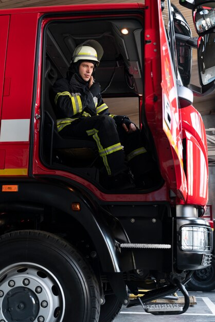 Male firefighter at station equipped with suit and safety helmet