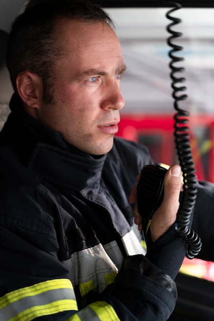 Free photo male firefighter using radio station inside fire truck