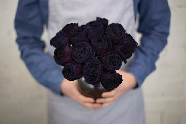 Free photo male florist in apron holding bright color rose bouquet in hand