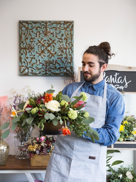 Free photo a male florist looking at flower decoration in his shop