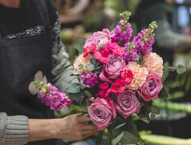 Male florist makinf a colorful flower bouquet